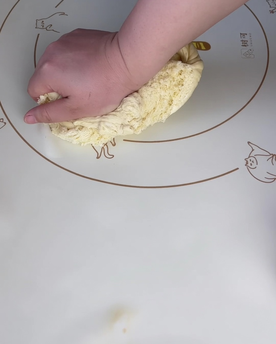 Mano che preme sullimpasto lievitato su un tappetino in silicone per eliminare laria.