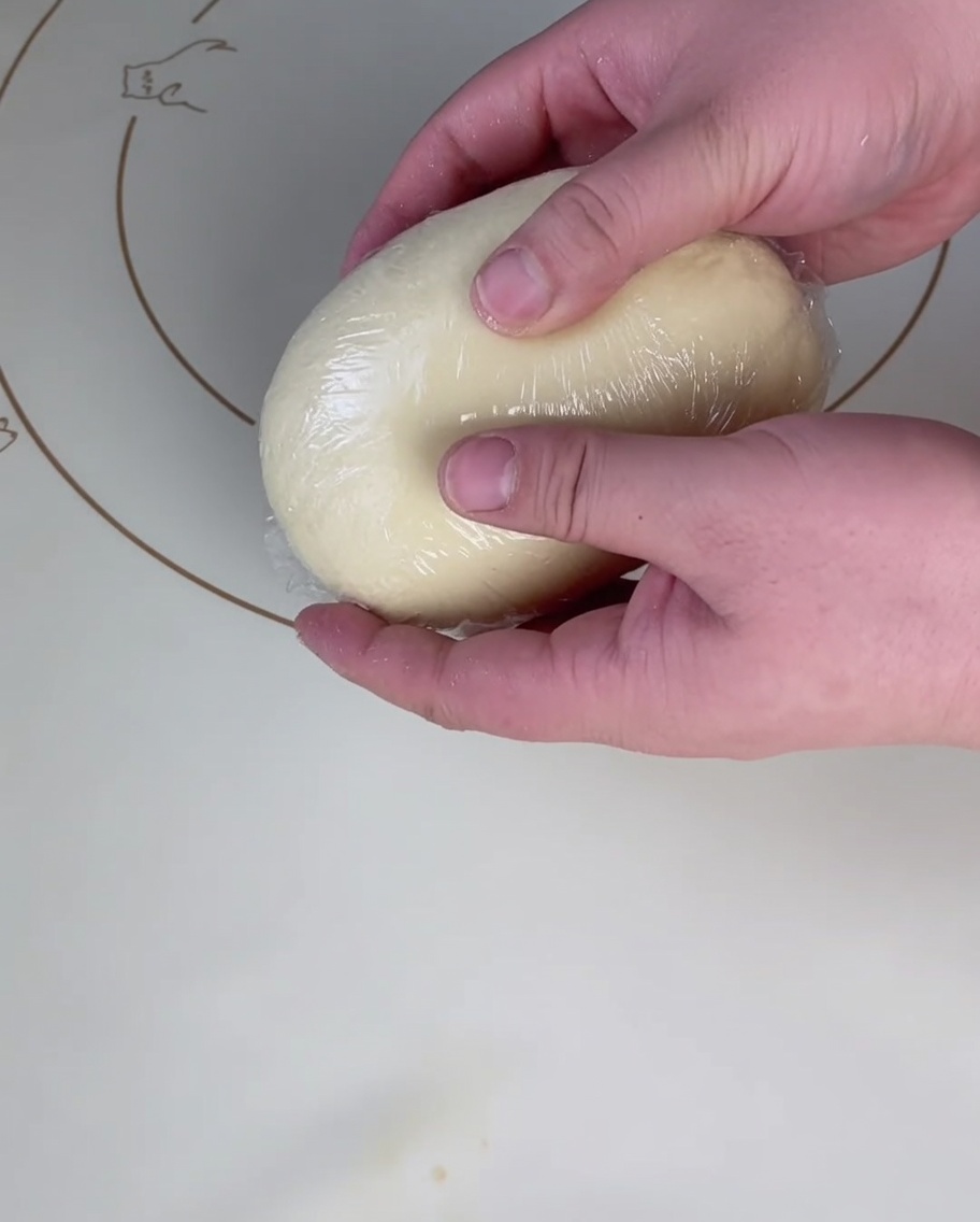 Palla di impasto coperta da pellicola su un tappetino.