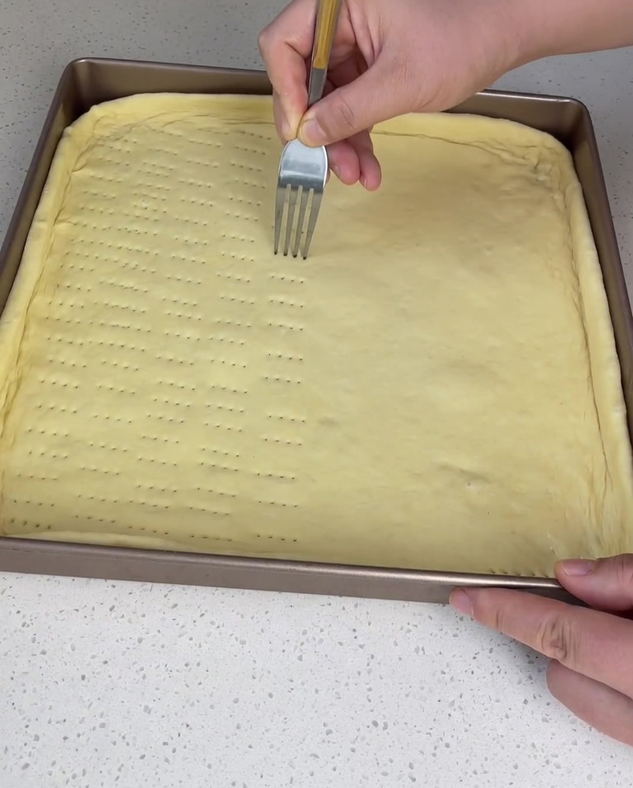 Una forchetta che crea piccoli fori su tutta la superficie dellimpasto.
