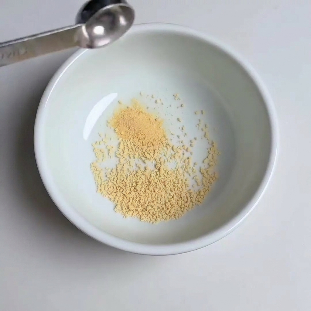 Cucchiaini che aggiungono aglio in polvere, zucchero e pasta gochujang nella ciotola.