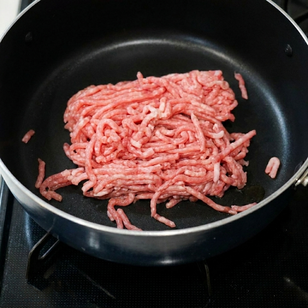 Carne di maiale macinata che sfrigola in padella con pasta di fagioli piccante e aglio.