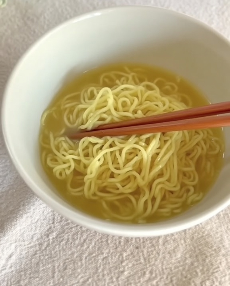 Brodo cremoso di Tantanmen versato sopra i noodle preparati in una ciotola.