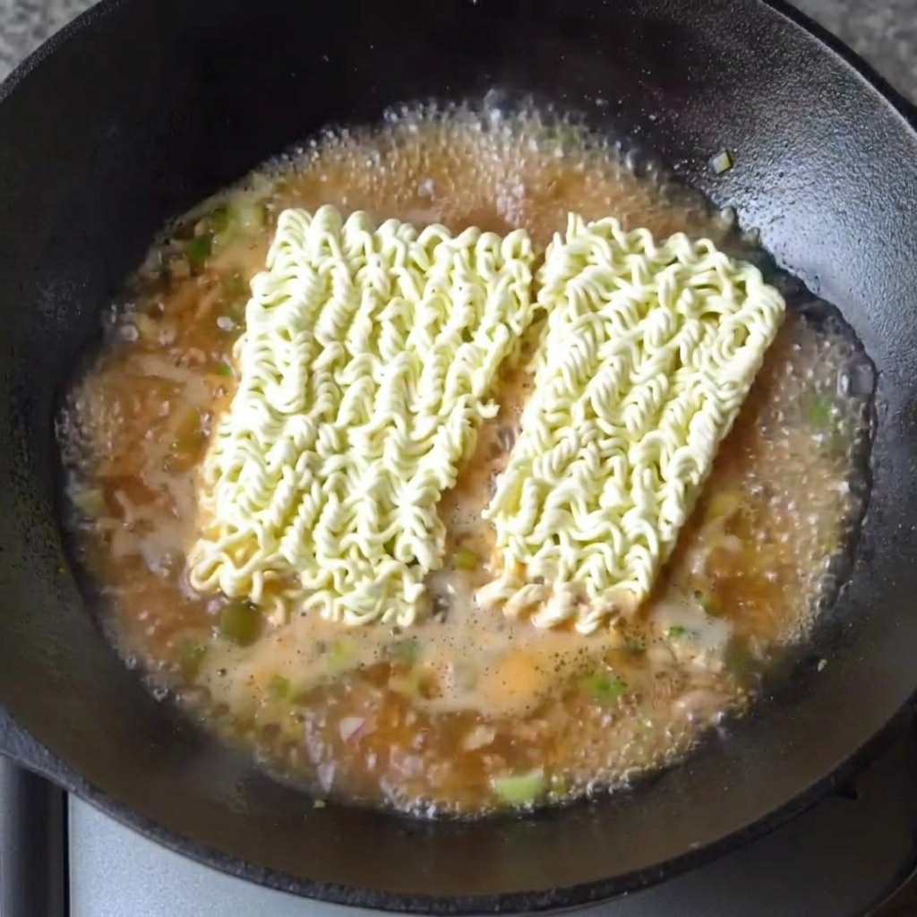 Due blocchi di noodle ramen secchi immersi nel brodo bollente saporito.