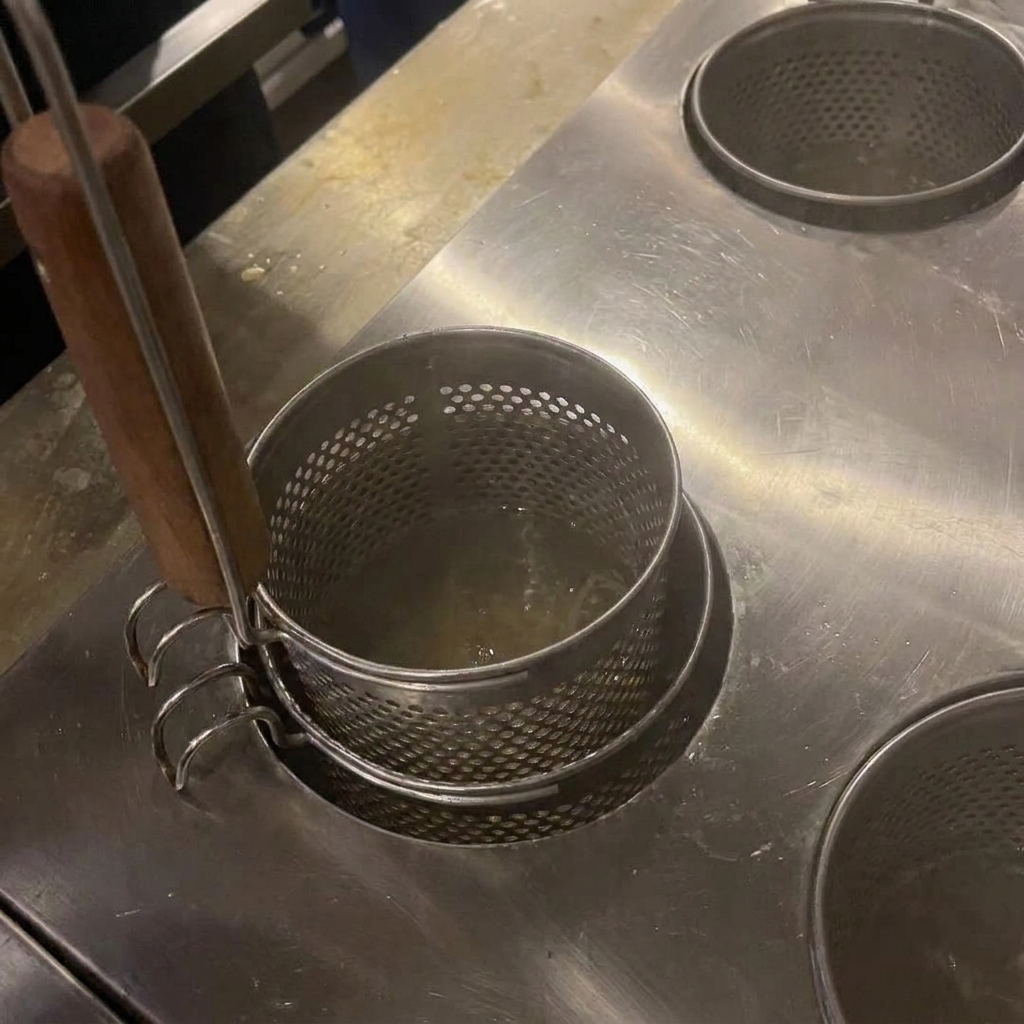 Noodle mescolati in acqua bollente con bacchette di legno.