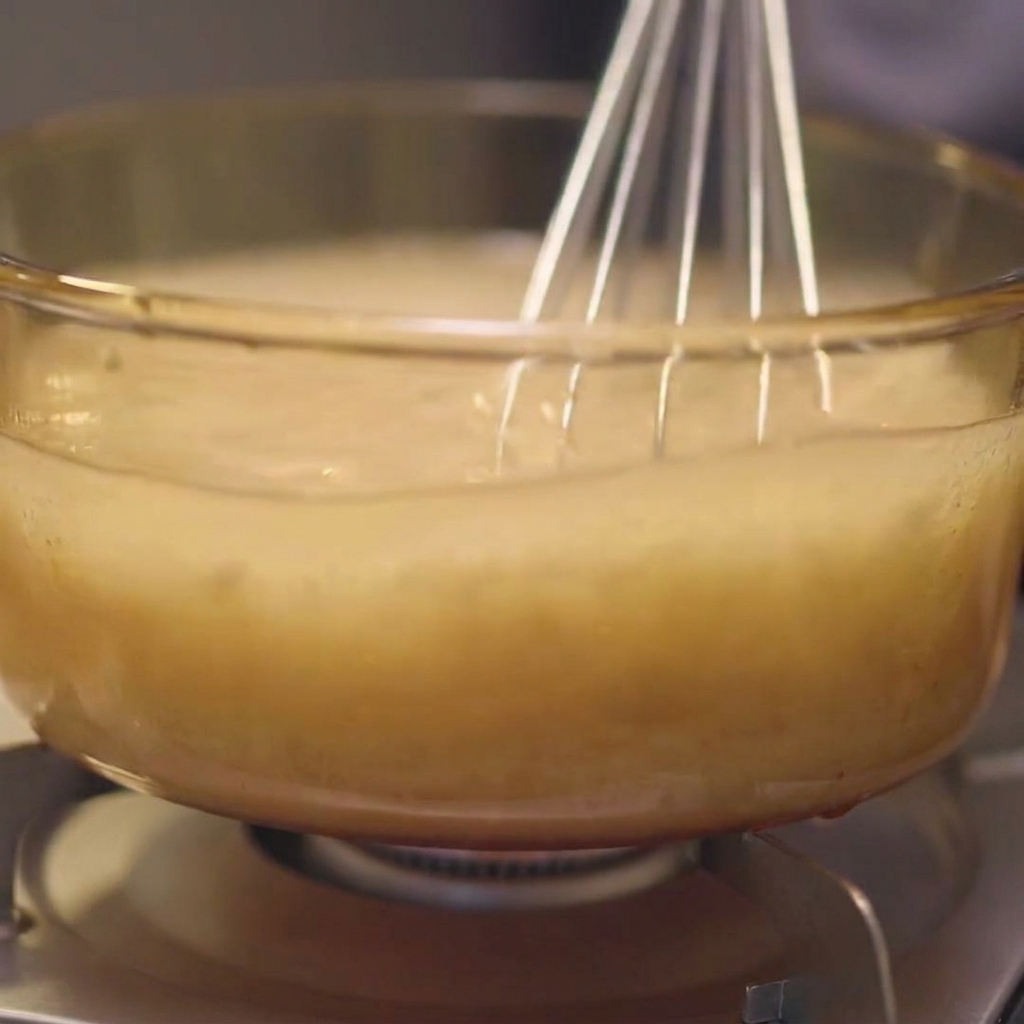 Pezzi di kombu immersi nel brodo di pollo in una pentola di vetro.