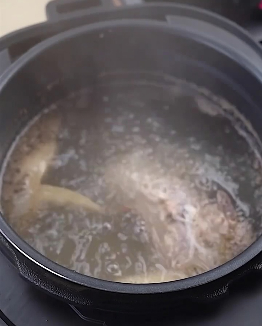 Ossa e piedini di pollo sciacquati in una ciotola di acciaio inox.