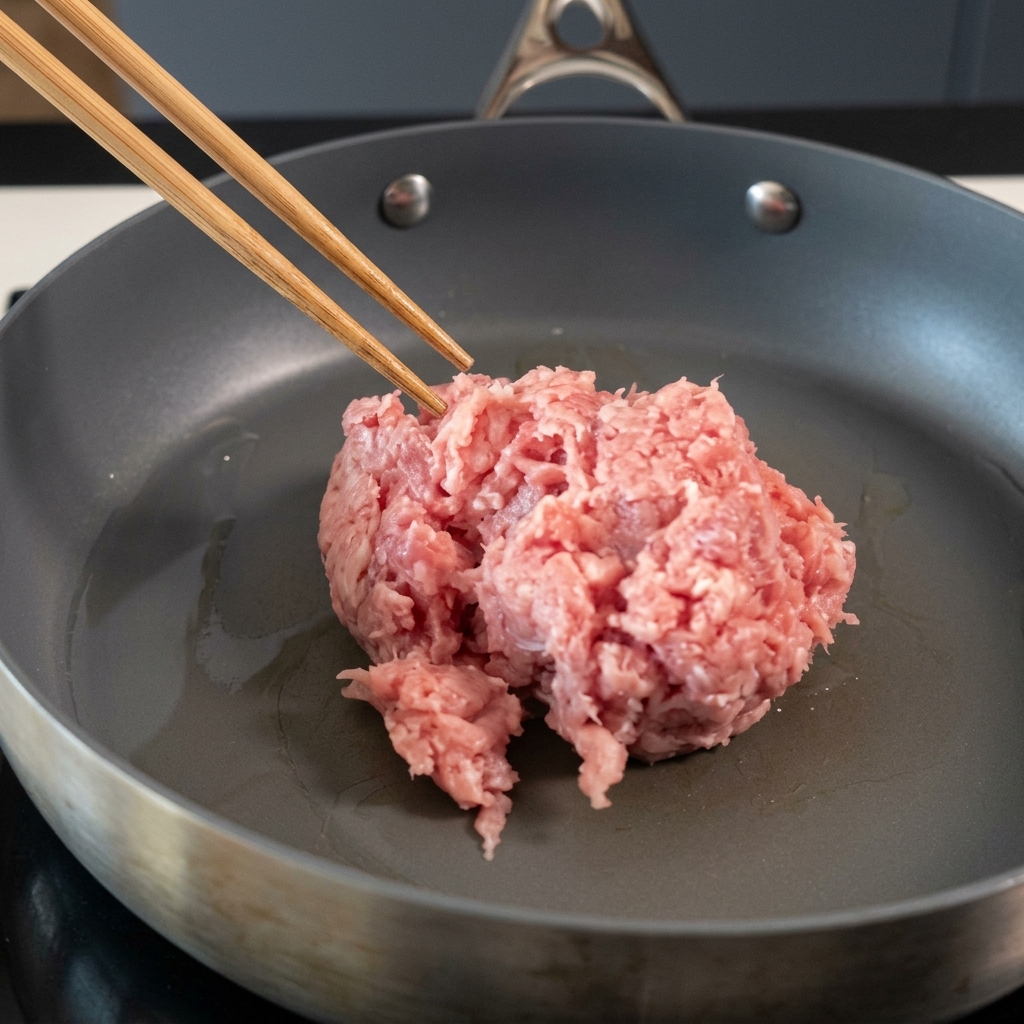 Maiale macinato mescolato in una padella antiaderente con le bacchette.