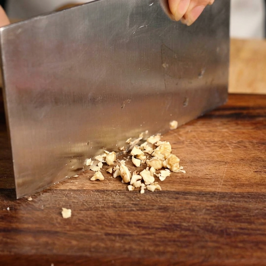 Scalogno fresco tritato finemente su un tagliere di legno con un coltello.