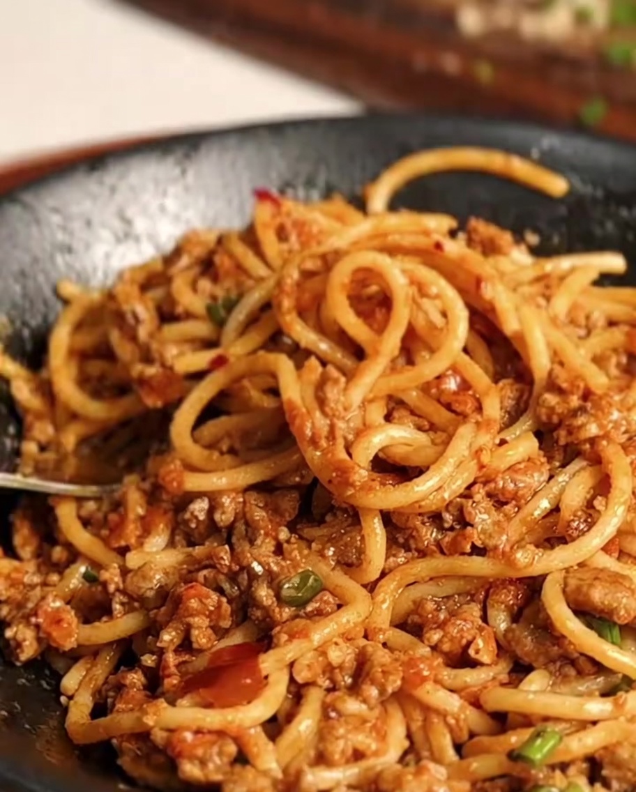 Saltare gli spaghetti e il sugo di carne insieme nella padella finché non sono uniformi.