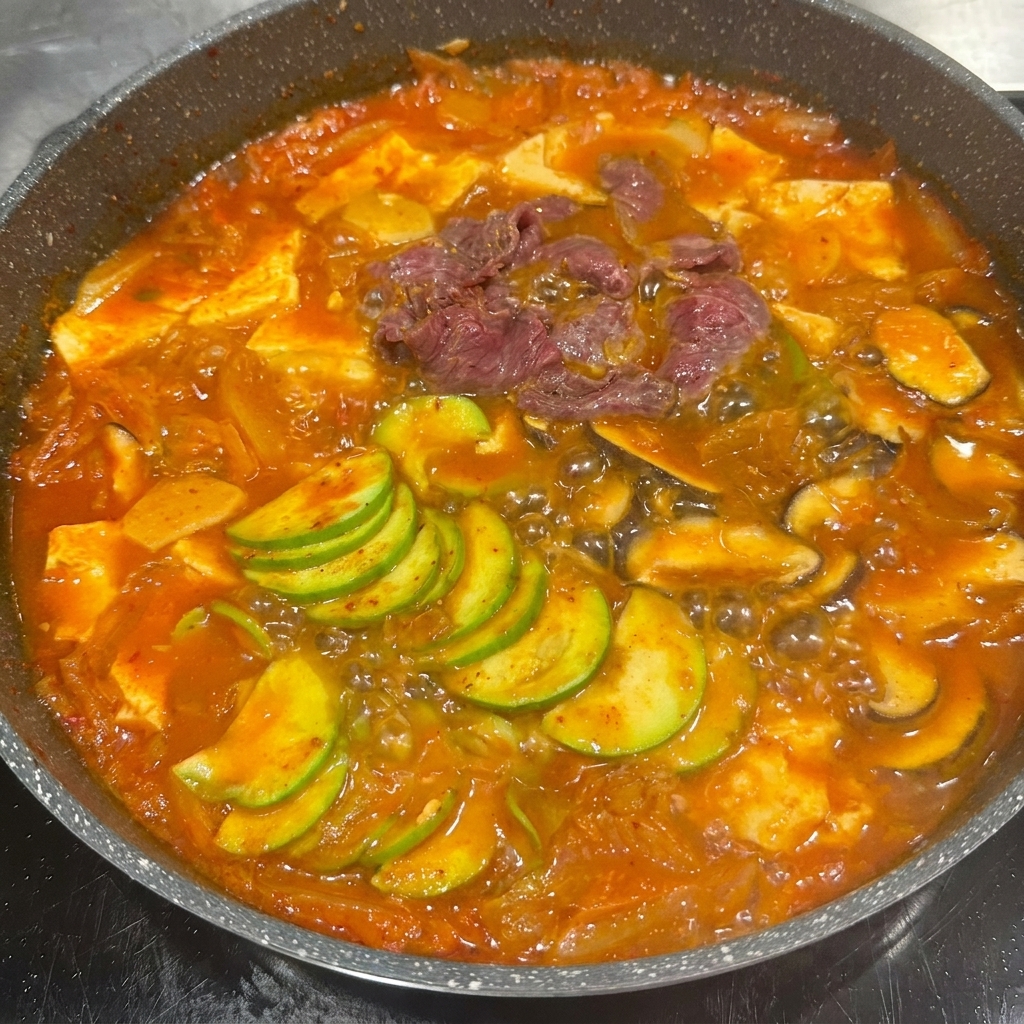 Fettine di manzo marinato poste nella pentola con le verdure e il brodo di kimchi.