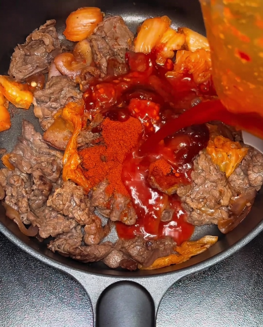 Acqua versata nella padella con il composto di manzo e kimchi.