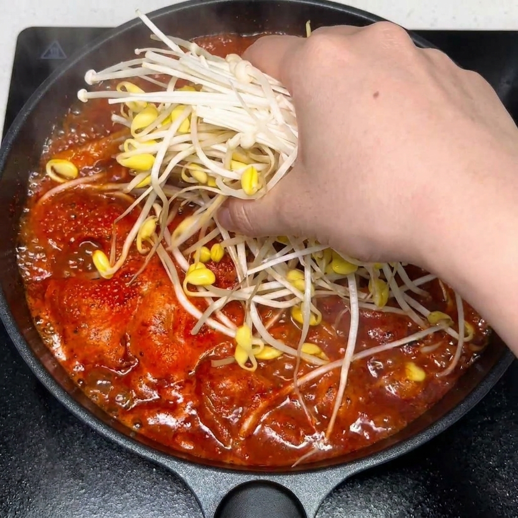 Aglio tritato e condimenti aggiunti alla zuppa piccante di kimchi e manzo.