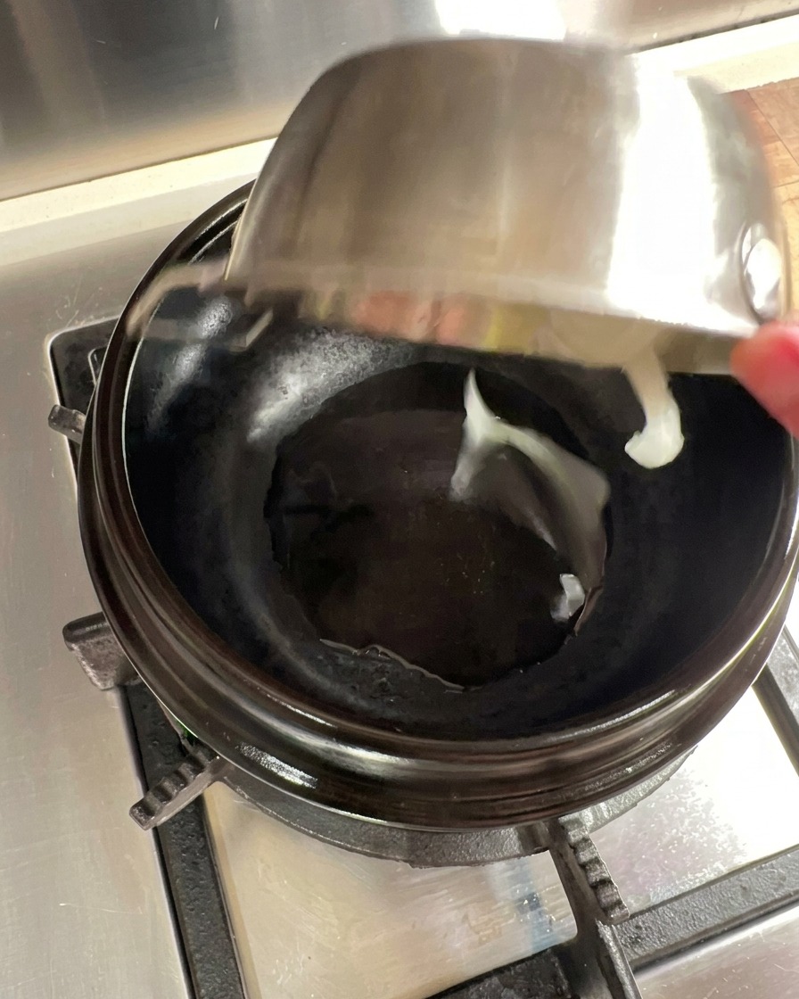 Fettine di cipolla saltate in una pentola di pietra preriscaldata con olio.