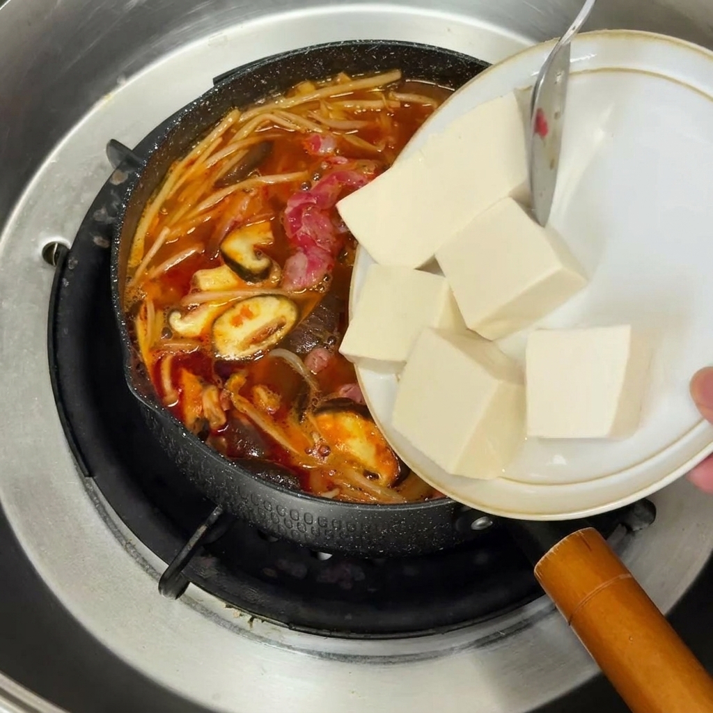 Cipolla rossa tritata che soffrigge in una padella gialla con olio luccicante.