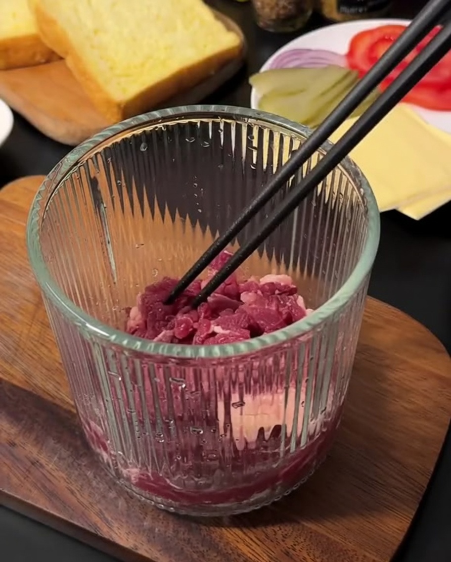 Macinato di manzo fresco crudo allinterno di un tritatutto manuale in vetro, pronto per essere lavorato.