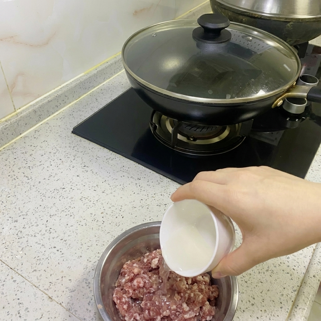 Acqua di cipolla e zenzero versata in una ciotola con carne macinata cruda.