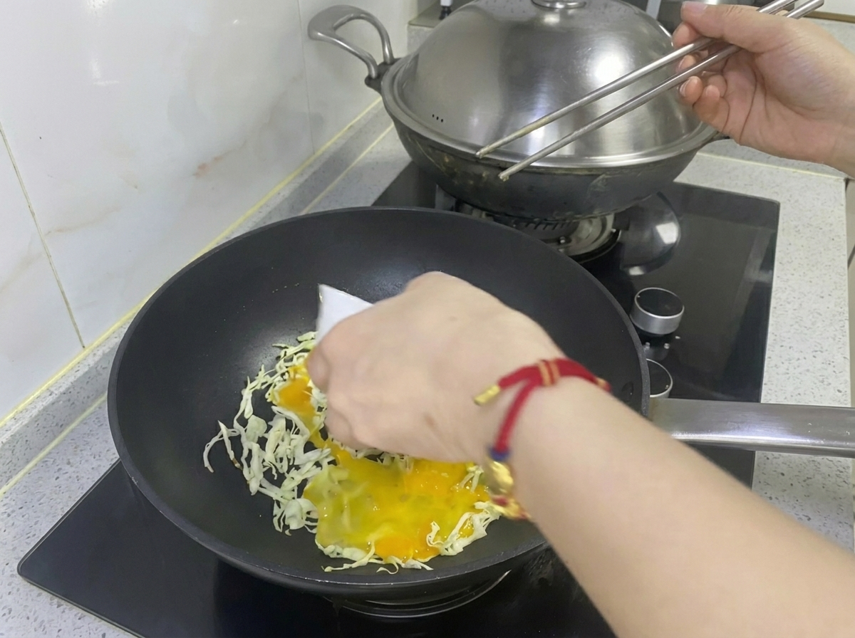 Uovo sbattuto versato sopra il cavolo tritato in una padella.
