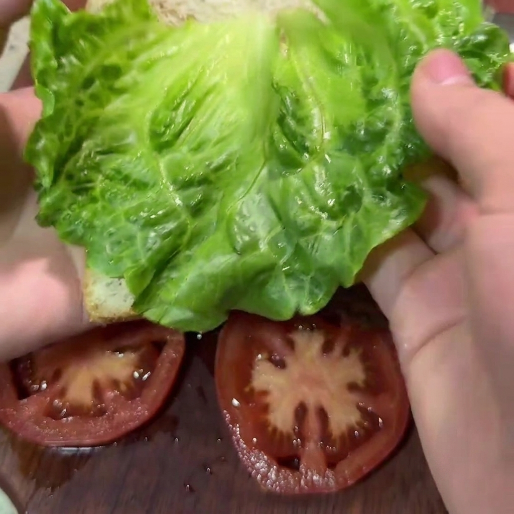 Un cucchiaio di legno che mescola il composto di manzo, verdure e spezie in una grande ciotola bianca.