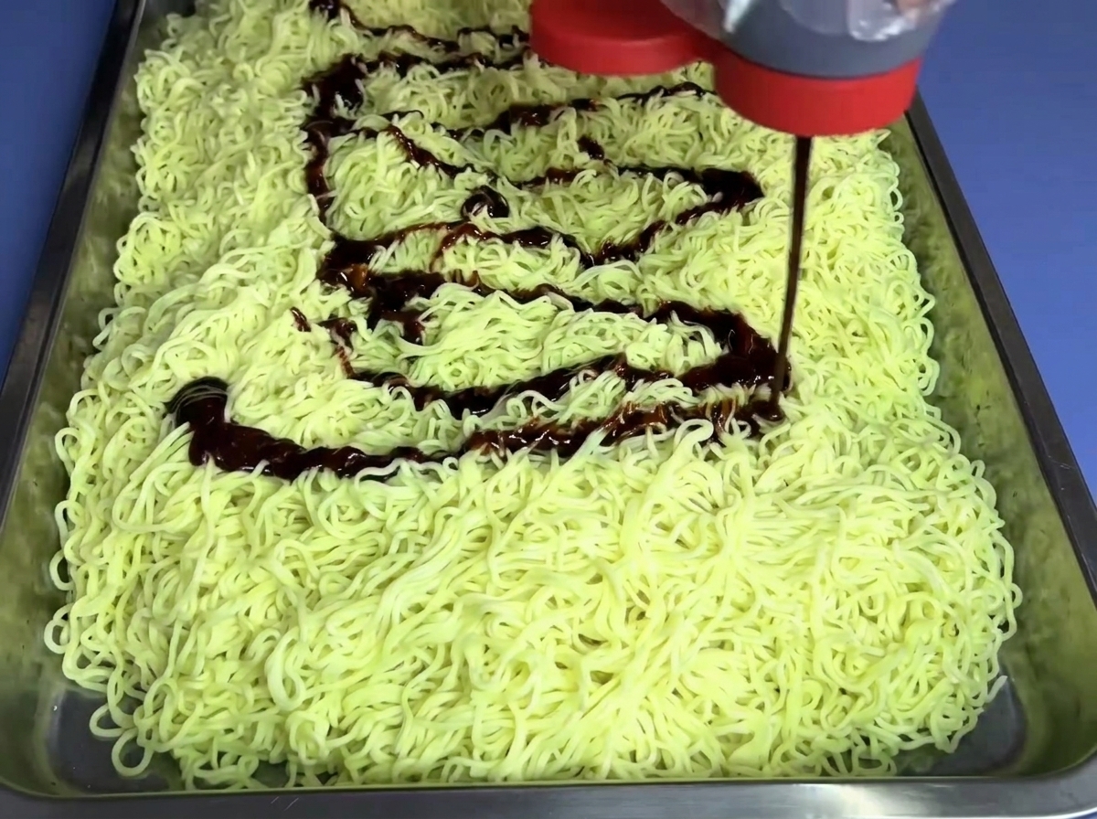 Salsa per noodles non piccante versata da un flacone su un letto di noodles.