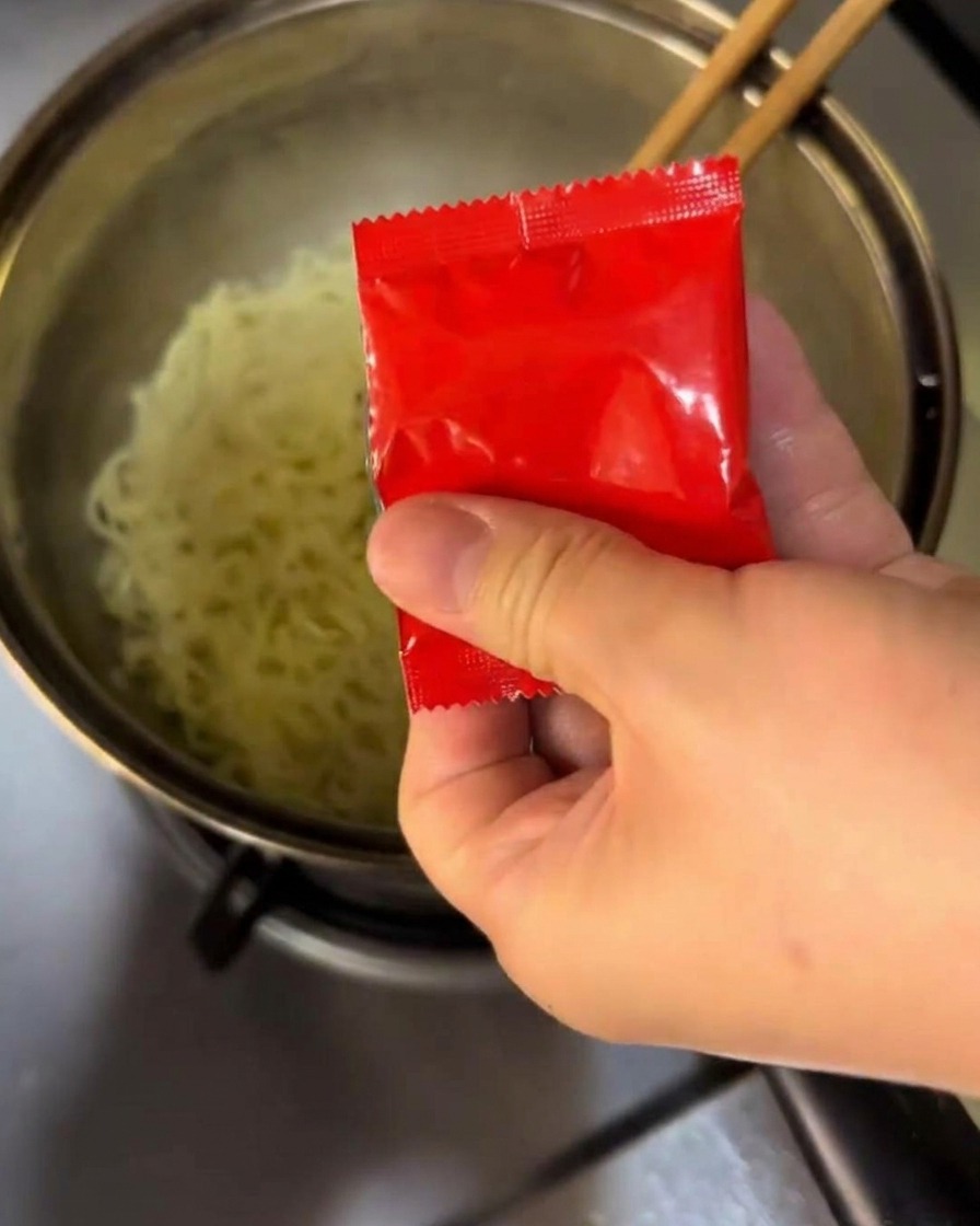 Mescolare il condimento e la salsa piccante nei noodles bollenti in una pentola.