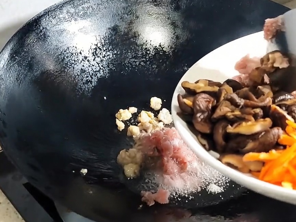 Funghi shiitake affettati e aromi aggiunti al maiale nel wok.