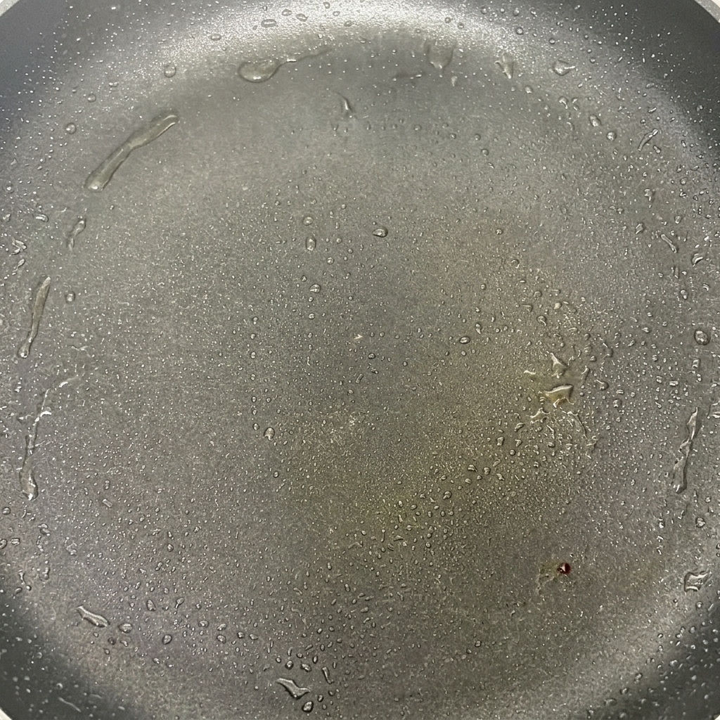 Cappelle di funghi che sfrigolano in una padella calda con olio, iniziando a dorarsi leggermente.