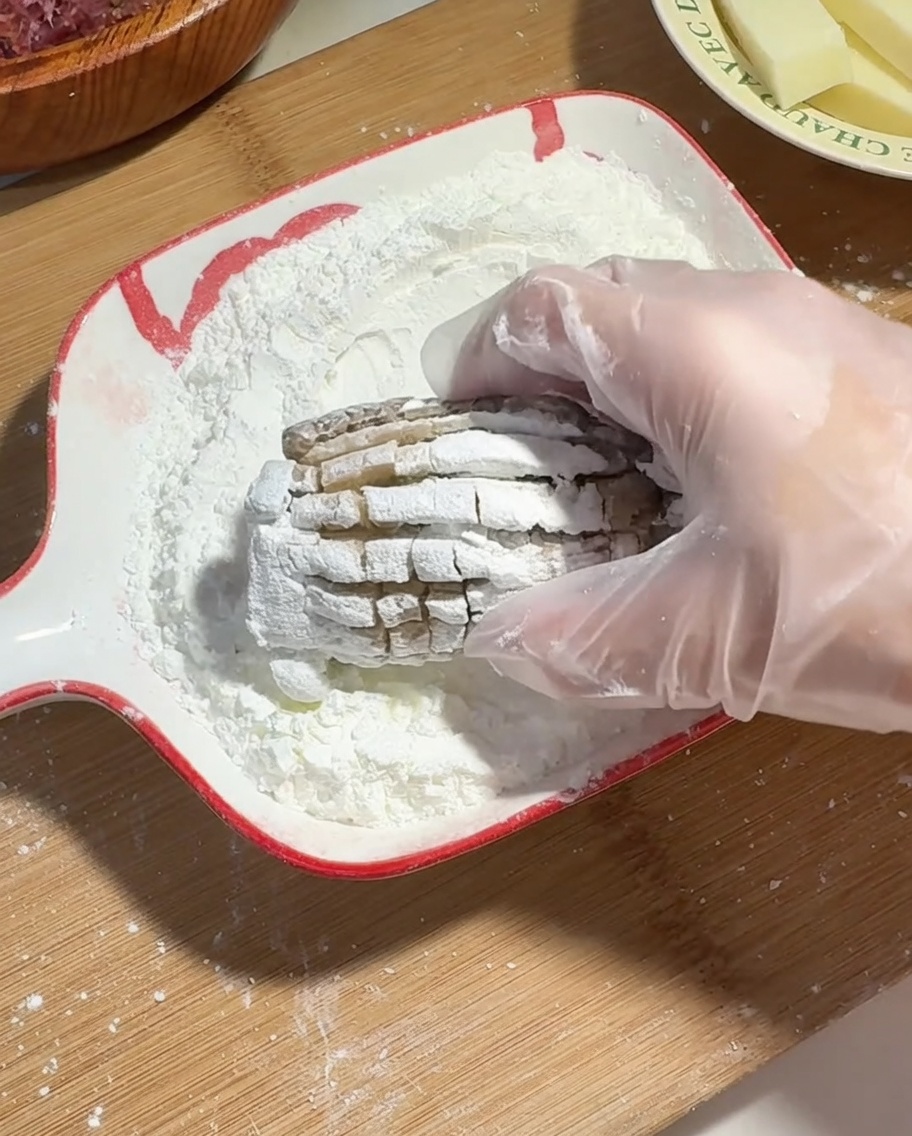 Una mano con guanto che riveste un fungo shiitake farcito di manzo e formaggio con amido di mais.