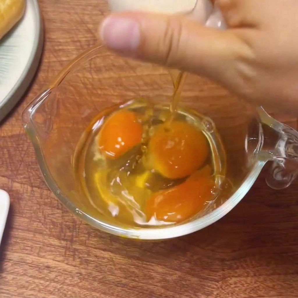 Uova fresche rotte in un misurino di vetro, pronte per essere sbattute.