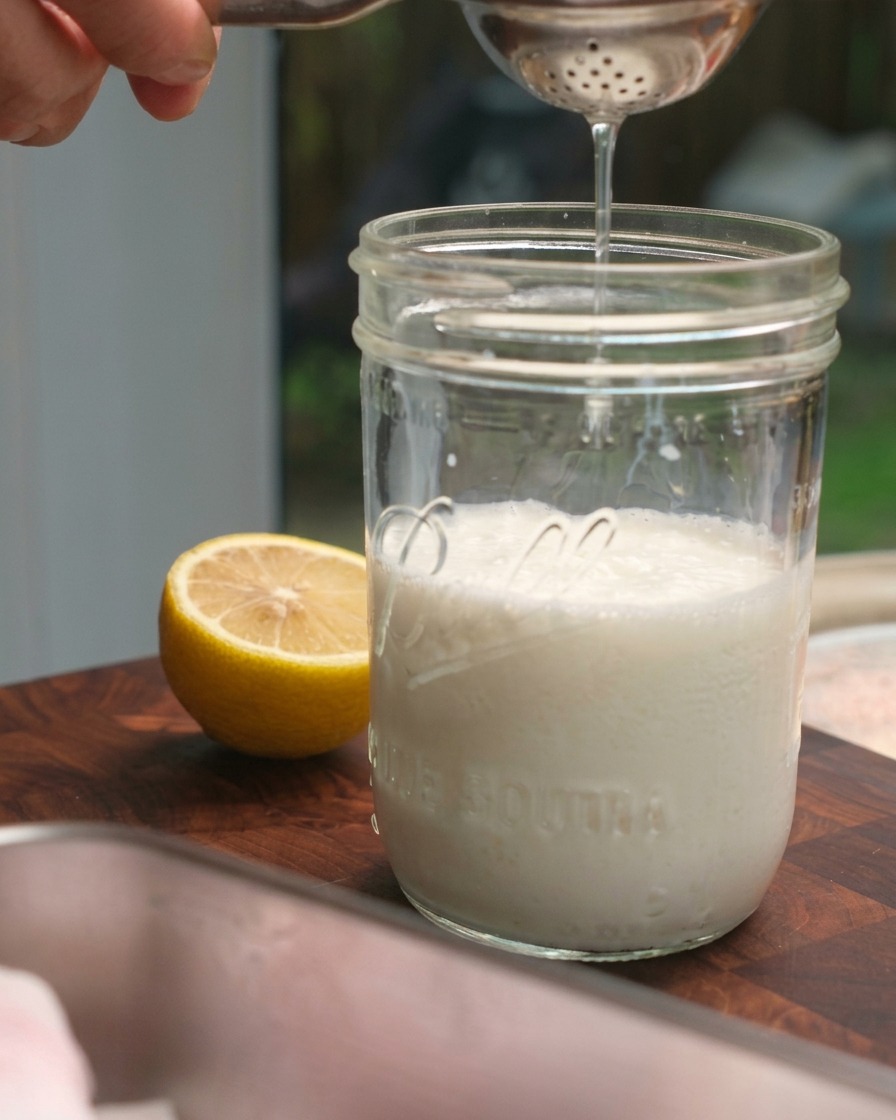Succo di limone fresco spremuto da uno spremiagrumi in un barattolo di vetro riempito di latte.