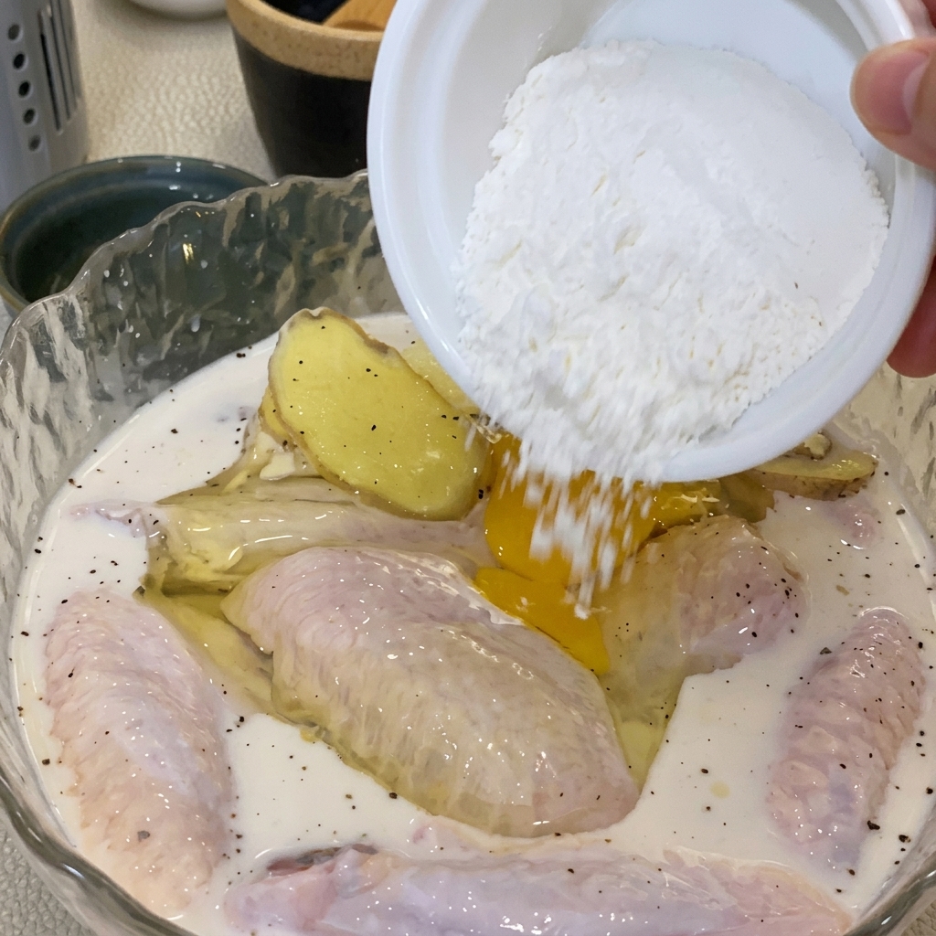 Una mano che mescola uova e farina nella ciotola del pollo per creare una pastella.