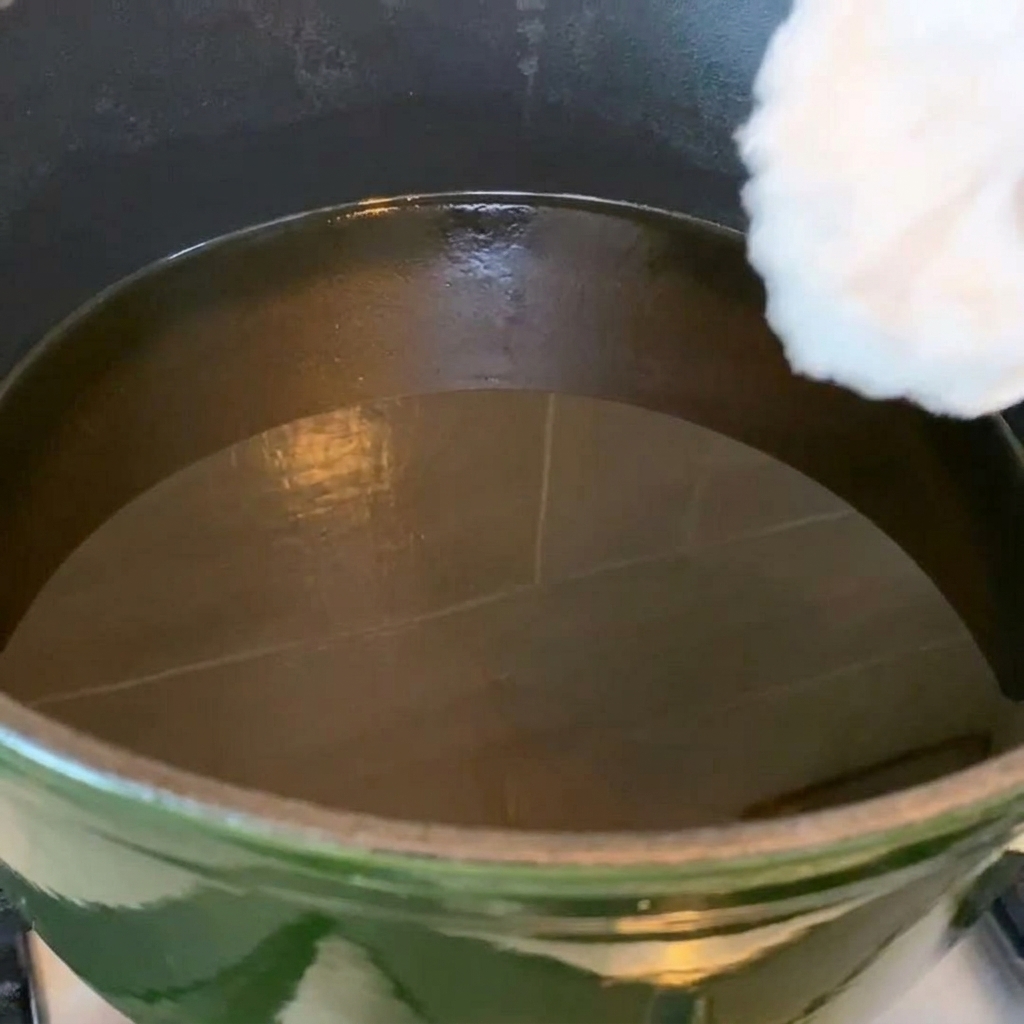 Ali di pollo che friggono in una padella con olio bollente, mostrando una colorazione dorata.
