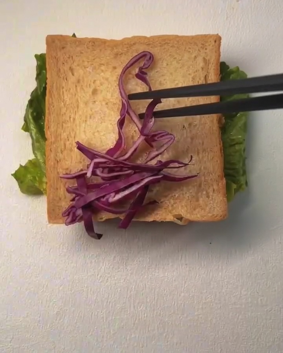 Una fetta di pane guarnita con cavolo viola tritato e chicchi di mais, con un filo di maionese sopra.