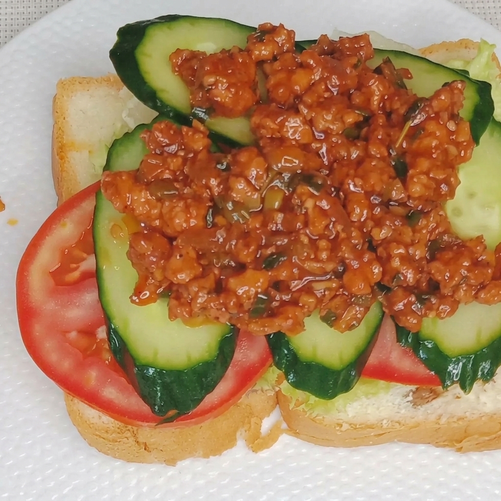 Primo piano di cremosa salsa al tuorlo duovo che viene versata a filo sopra uno strato di ragù di carne su un panino.