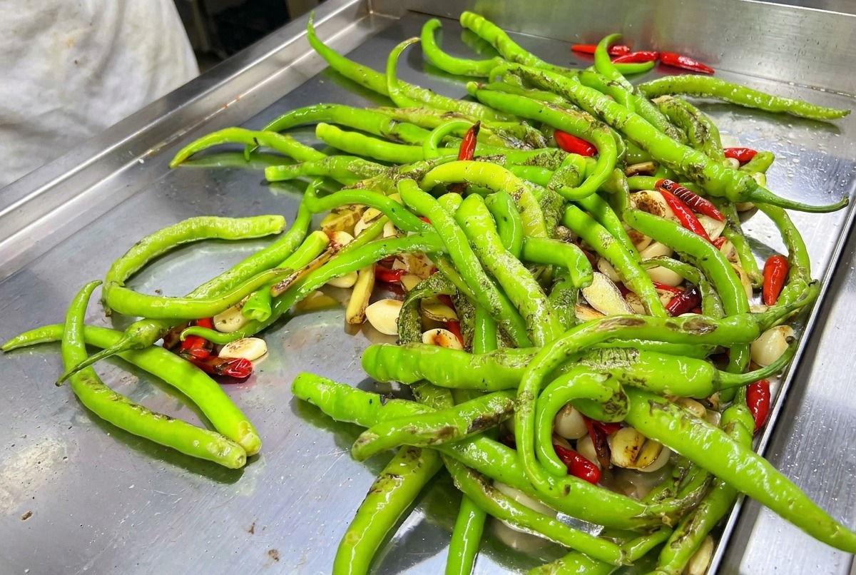 Un mix di peperoncini verdi e rossi bruciacchiati col cannello su una piastra calda.