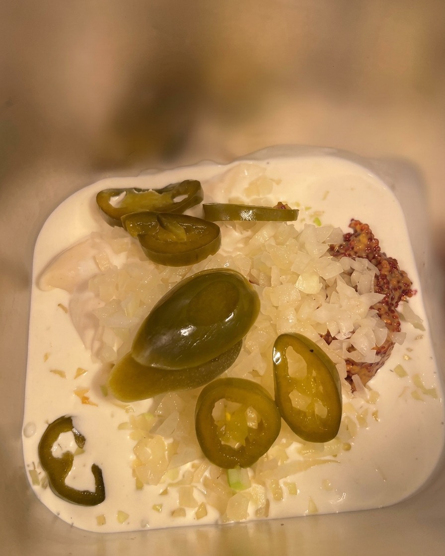 Ketchup versato nel contenitore di metallo contenente il resto degli ingredienti della salsa.