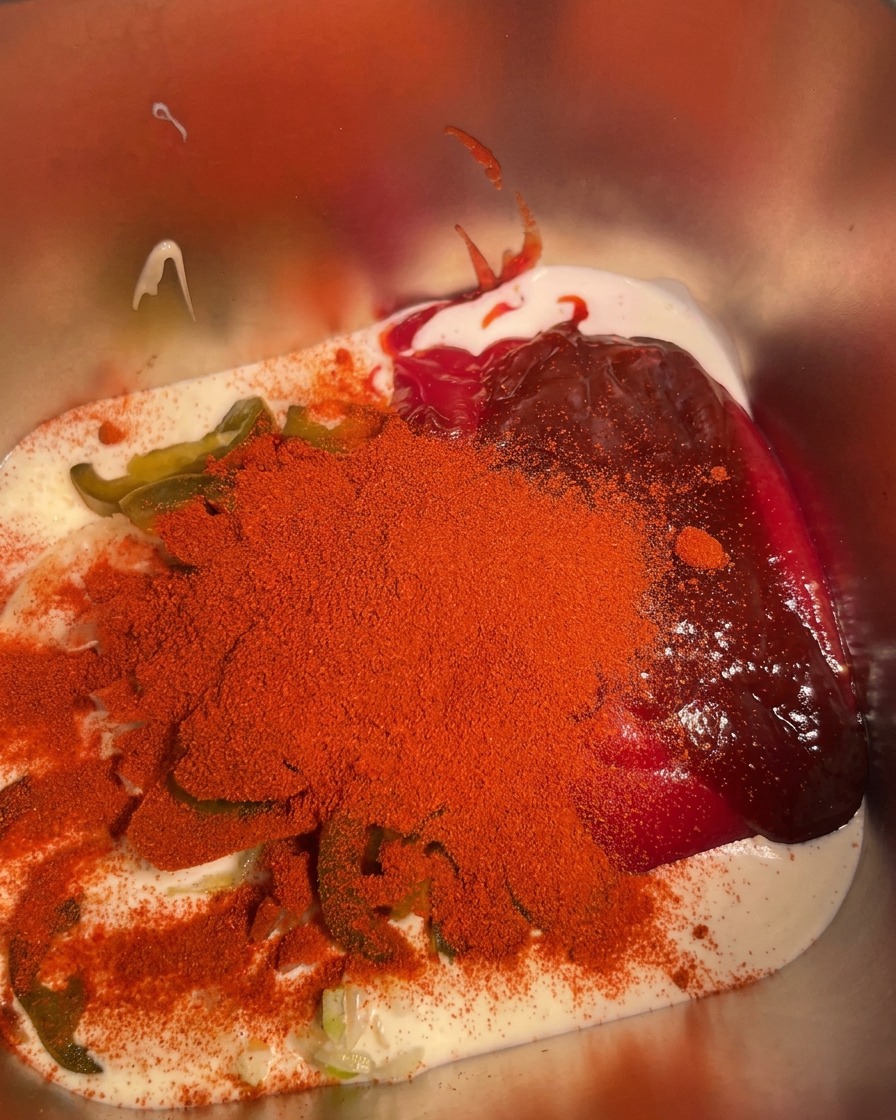 Aglio in polvere cosparso sugli ingredienti combinati nel contenitore di metallo.