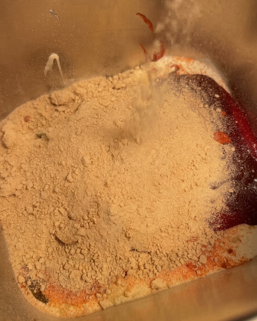 Un frullatore a immersione che mescola gli ingredienti allinterno di un contenitore di metallo fino a ottenere un composto omogeneo.