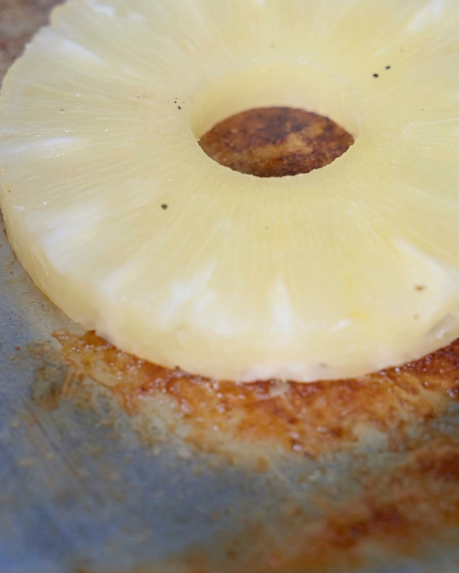 Una singola fetta di ananas che griglia su una superficie calda e scura della piastra.