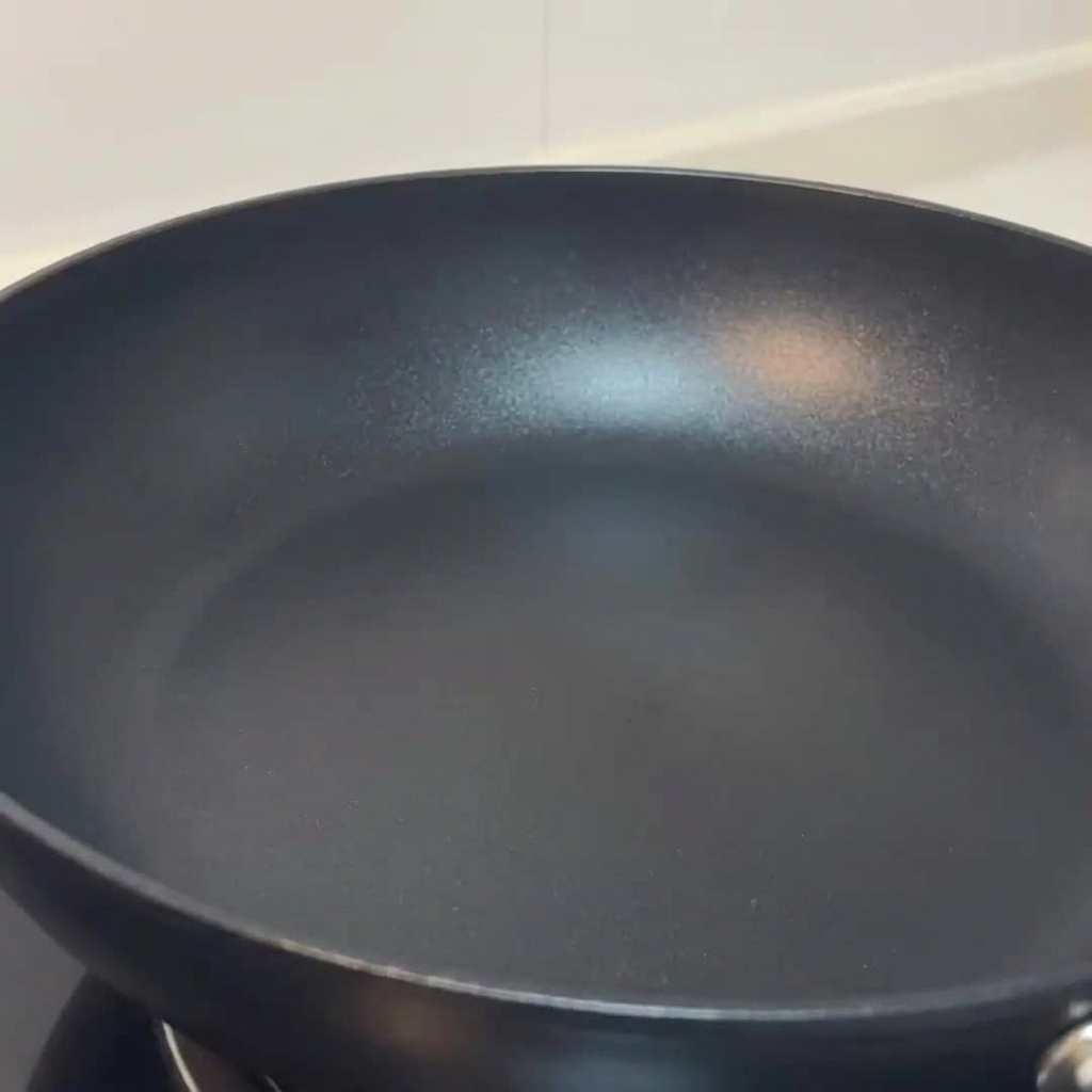 Funghi affettati che friggono in una padella, conditi con sale e pepe nero.