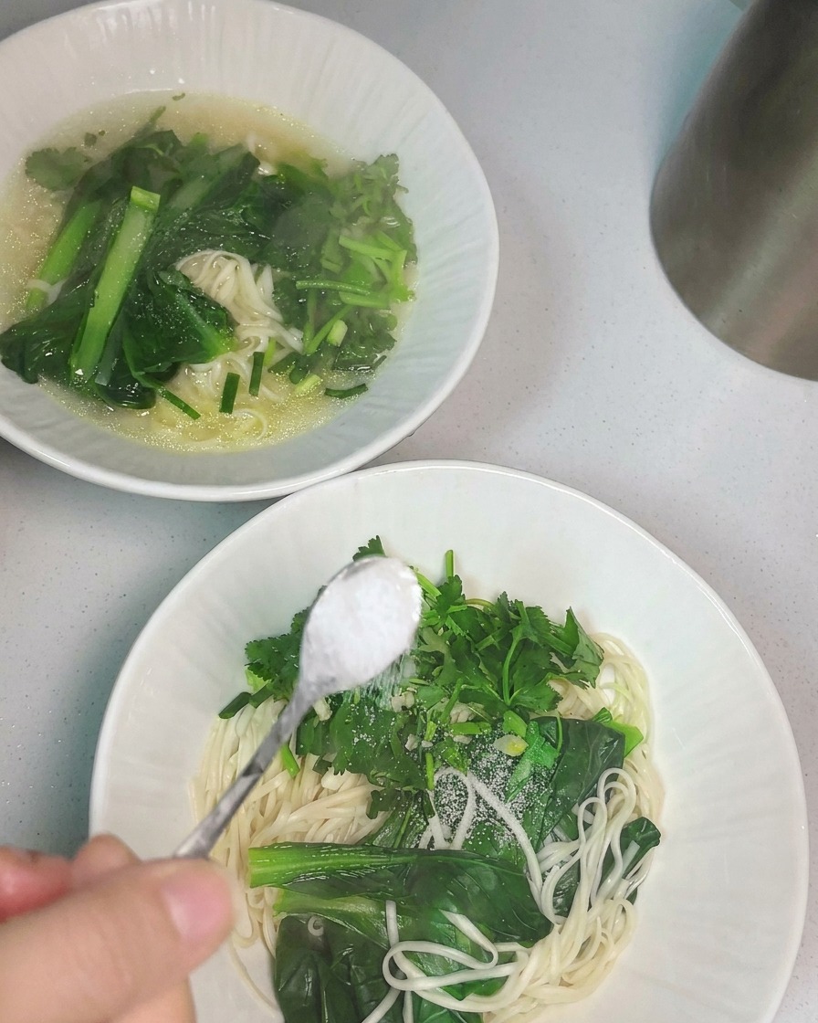 Zuppa di pollo calda versata con un mestolo in una ciotola di noodles.