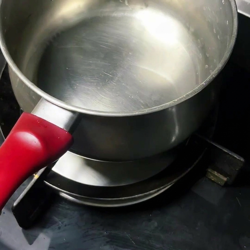 Un uovo crudo che cuoce in una pentola dacciaio pulita sul fornello.