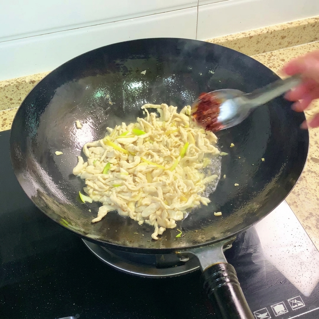 Pasta di fagioli Pixian aggiunta al wok e mescolata con il composto di pollo.