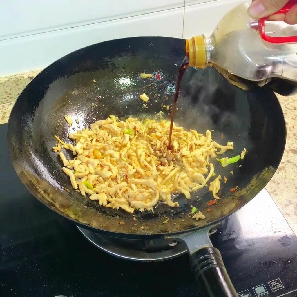 Salsa di soia scura versata nel wok con il pollo saltato.