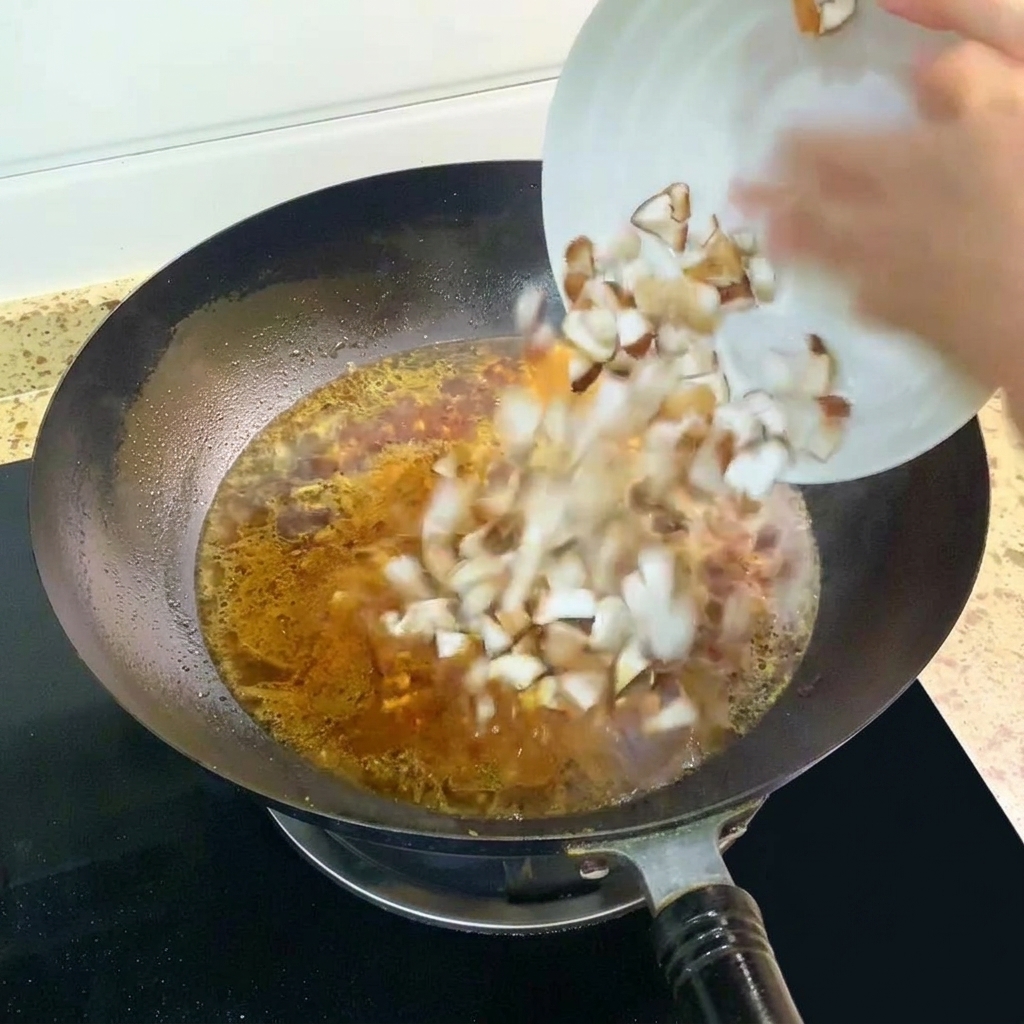Funghi shiitake a cubetti aggiunti al brodo bollente nel wok.
