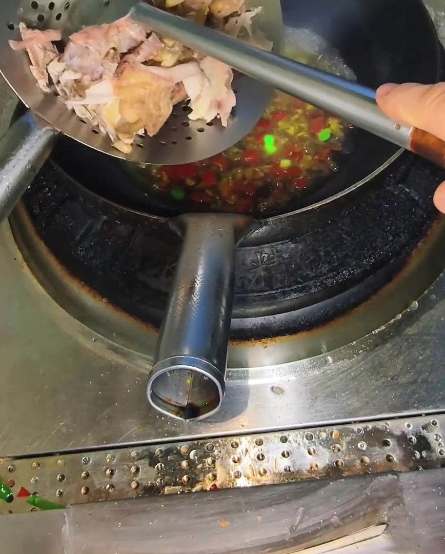 Pollo sfilacciato aggiunto al brodo nel wok.