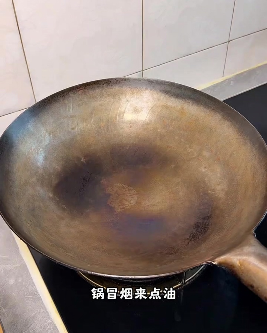 Un wok rovente sul fornello con volute di fumo visibili.