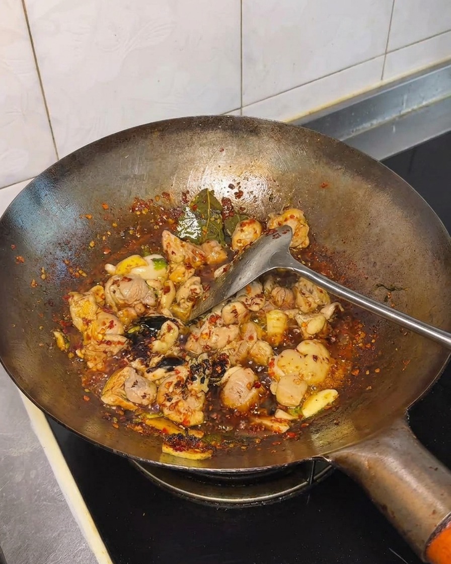 Salsa di soia e condimenti incorporati nel pollo saltato nel wok.