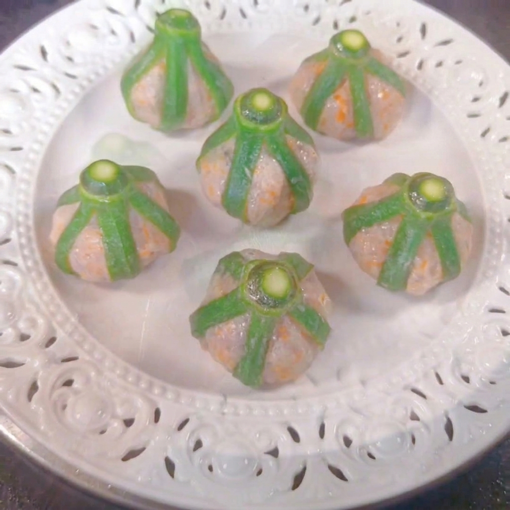 Sei bocconcini di gombo e gamberi disposti su un piatto bianco allinterno di una vaporiera.