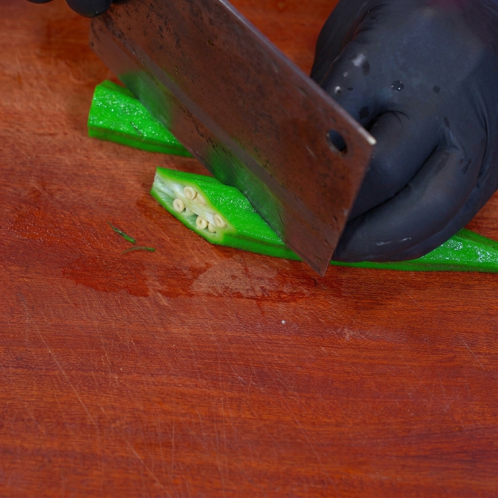 Okra sbollentata tagliata a forma di diamante su un tagliere di legno.