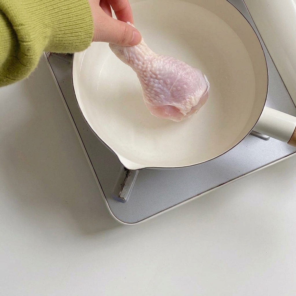Fusi di pollo che cuociono a fuoco lento in una pentola con aromi.